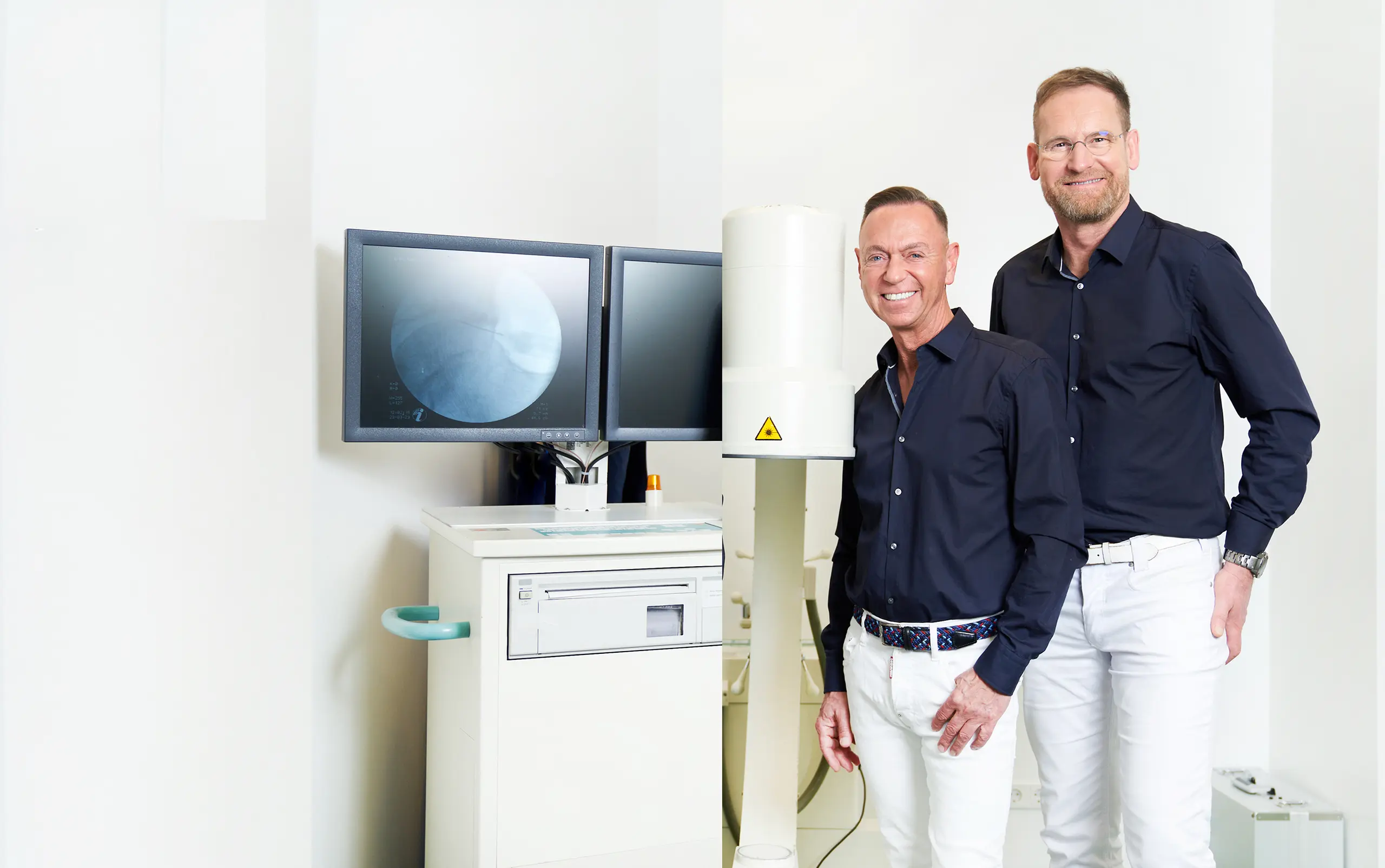 Zwei Ärzte der orthopädischen Praxis Orthopädicum Düsseldorf vor Praxisgeräten